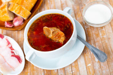 Appetizing Russian dish borscht served with sour cream, bread and salo in a cafe