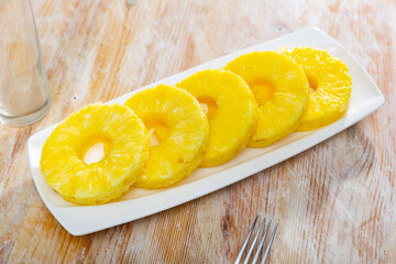 Juicy fruit, sliced pineapple served on wooden table.