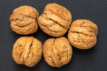 Whole walnuts in shell isolated on black faux leather
