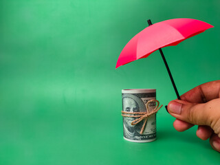 Hands holding red umbrellas to protect banknotes, save families, prevent risk and the concept of insurance.