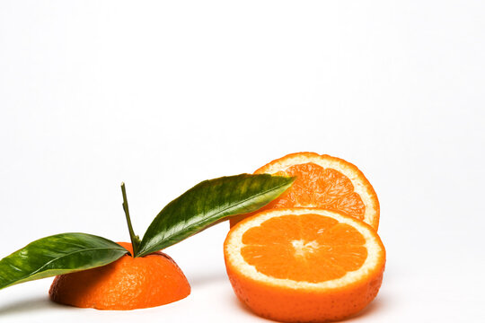 Cut Orange fruit with leaves isolated on white. © SimoneO