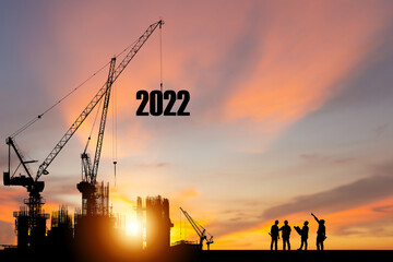 Silhouette of construction worker with crane and sunset sky for preparation new year of 2022