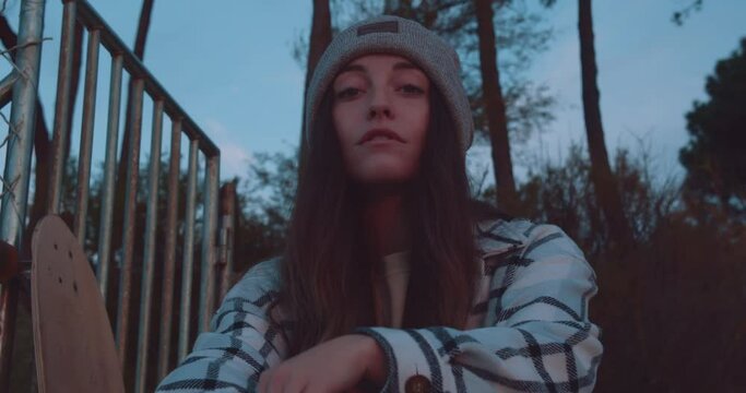 Serious European Woman In Beanie Hat And Casual Long Sleeve Shirt Sitting Outdoor Looking At The Camera. medium shot