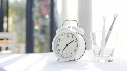 Toothbrush, toothpaste and towel and healthcare concept, glass of water, vintage white alarm clock