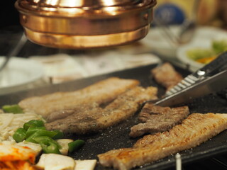 grilled pork is on the pan in Thai style, Thai buffet with pork, chicken and other meats, cooked on brass barbecue pan, pork grill, Bar-B-Q, Korean Barbecue in Thai Style, Thai Barbecue Buffet