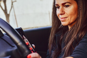  Beautiful happy smiling woman drinking hot coffee takeaway cup inside a car and using smartphone  while driving the car in the morning during going to work 