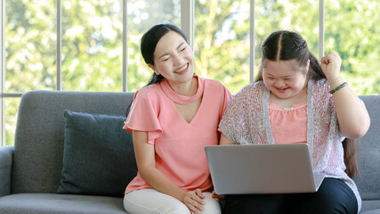 Asian young chubby down syndrome autistic daughter learning mathematic lesson from happy mother via laptop computer at home. Teacher teaching counting number with fingers to autism student in school