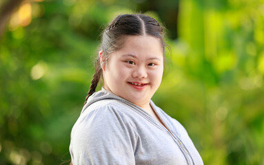 Portrait shot of Asian young chubby down syndrome autistic autism little cute schoolgirl with braid...