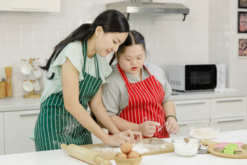 Asian lovely mother encouraging teaching young chubby down syndrome autistic autism pastry chef...