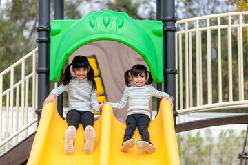 Child playing on outdoor playground. Kids play on school or kindergarten yard. Active kid on colorful slide and swing. Healthy summer activity for children.