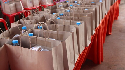Fototapeta premium A water bottle and snacks are placed in a brown paper bag on a red table.