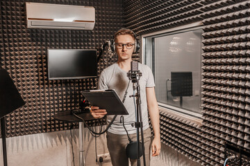 The vocalist sings in the studio in a microphone. Man in headphones writes a podcast, an audiobook....