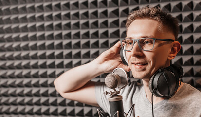 The vocalist sings in the studio in a microphone. Man in headphones writes a podcast, an audiobook. Artist, recording an album, working with the label. Announcer records a speech at a radio station