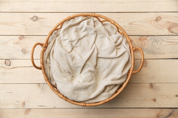 Round wicker basket with a blanket for newborns on a  wooden floor