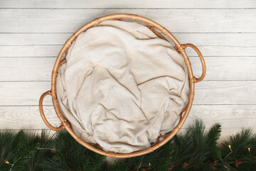 Round wicker basket with a blanket for newborns on a  wooden floor