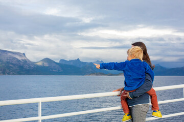 Child and mom, cute blond boy with mother, looking at the mountains from a ferry in Nortern Norway