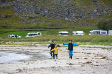 Happy children, enjoying white sand beach in Norway, running and playing with water on summer day