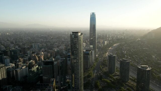 Aerial view of the financial center of santiago de chile with its towers being illuminated by the sun at dusk - crane shot