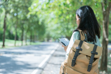 Young female tourist with casual clothes and backpack is using smart phone to  find new place, new way to travel in differnt and new tourist attraction. Inspirational travel concept