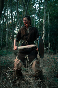 Angry female viking with weapon and shield during battle reconstruction