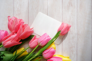 Beautiful color tulip flowers composition with blank card on white wooden table. floral background for Mother's day, Women's day, Easter and Spring time.