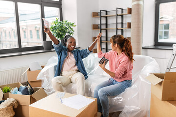 moving, finances and real estate concept - happy women with money, bills and calculator at new home making high five gesture