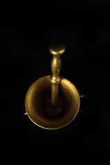 Low key closeup photo of brass mortar against black. Vertical photo with copy space in upper part of image. Top view, high angle.
