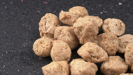 Raw soya chunks on dark background. Healthy, nutritious soybean meat, chunks isolated.Vegan food concept.
