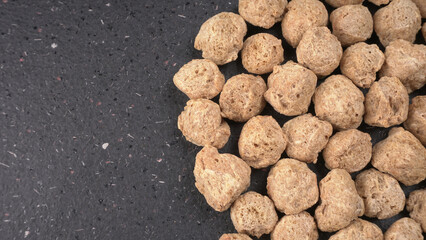 Raw soya chunks on dark background. Healthy, nutritious soybean meat, chunks isolated.Vegan food concept.