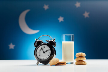 bedtime, sleeping and diet concept - close up of alarm clock, glass of milk and oatmeal cookies...