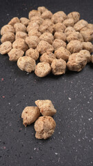 Raw soya chunks on dark background. Healthy, nutritious soybean meat, chunks isolated.Vegan food concept.