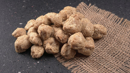 Raw soya chunks on dark background. Healthy, nutritious soybean meat, chunks isolated.Vegan food concept.