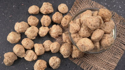 Raw soya chunks on dark background. Healthy, nutritious soybean meat, chunks isolated.Vegan food concept.
