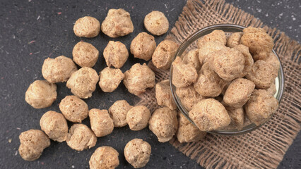 Raw soya chunks on dark background. Healthy, nutritious soybean meat, chunks isolated.Vegan food concept.