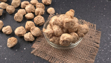Raw soya chunks on dark background. Healthy, nutritious soybean meat, chunks isolated.Vegan food concept.