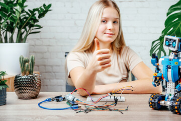 A teenager girl with her thumb up studying robotics at home, stem and arduino coding classes for children