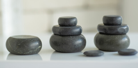 Closeup shot of Thai massaging spa therapy stuffs stack of burning hot volcanic massage black rocks and pebble stones placing on table preparing for customer treatment in front blurred background