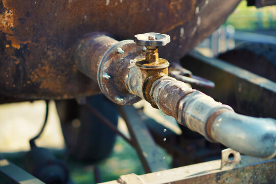 Dripping tap of a water tank in the open . Drops fall from the pipe