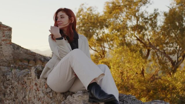 Giovane ragazza con cappotto bianco esplora un castello antico in Italia