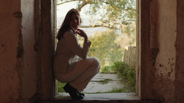 Giovane ragazza con cappotto bianco esplora un castello antico in Italia