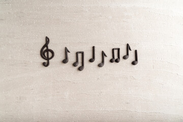 Black music violin clef sign and note on rough beige surface. G-clef. Treble clef. Space for text
