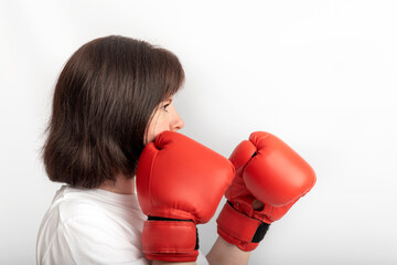 Portrait of young female boxer in red gloves on white background. Struggle for womens rights,...