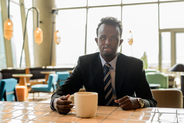 Portrait of African businessman wearing suit and tie in coffee shop