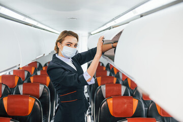 In mask. Young stewardess on the work in the passanger airplane