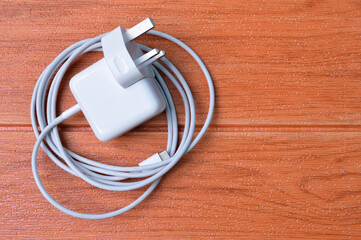 Laptop charging plug with USB type-c cable isolated on a wooden background.