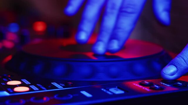 Male hand of professional DJ turns disc on DJ stereo control for sound quality and frequencies. Professional audio music in nightclub, entertainment concept