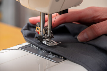 Sewing process. Close-up of repairing clothes, sewing on a sewing machine. Clothing repair concept.
