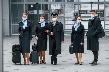 Aircraft crew in work uniform is together outdoors in the airport