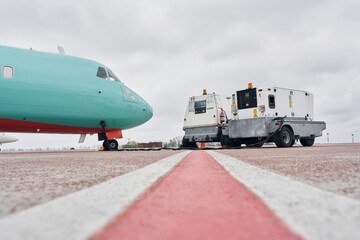 Vehicle nearby. Turboprop aircraft parked on the runway at daytime