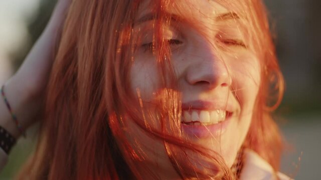 bella donna con capelli rossi sorride al vento